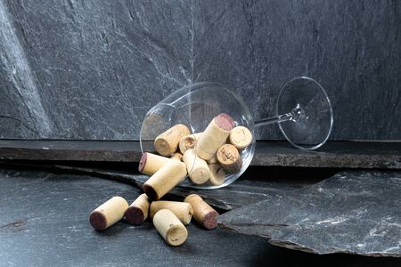 Wine glass filled with corks on dark gray stoneの写真素材