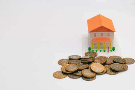 Miniature house with many coins ahead with space to write to rightの写真素材