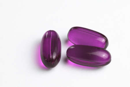 purple medicine capsules on white background in center photographyの写真素材