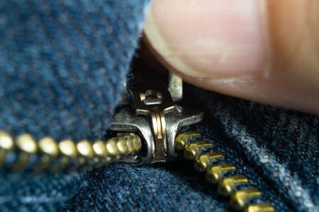 Bronze zipper on blue trousers and finger viewの写真素材