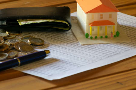 Wallet, playhouse, pen and coins on the accounting sheetの写真素材