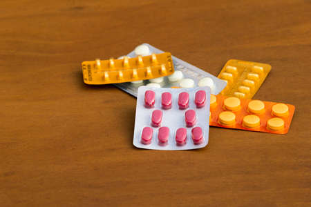 Several blisters packs medicine of various colors of tablets on wooden backgroundの写真素材