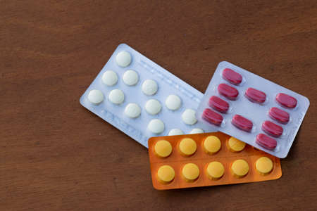 Several blisters packs medicine of various colors of tablets on wooden backgroundの写真素材
