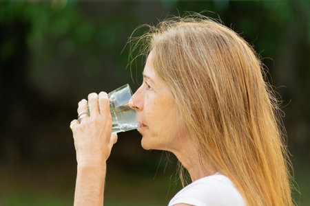 woman in profile drinking water from the glass tumblerの写真素材