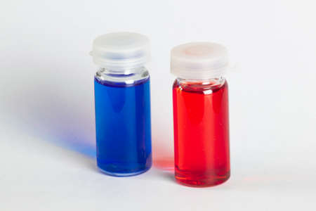 Two small transparent containers whit red and blue liquid in the center photography on white backgroundの写真素材