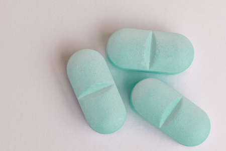 Three light blue medicine tablet on white background