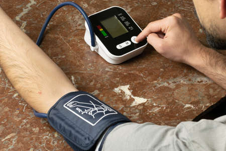 Person taking blood pressure with electronic deviceの写真素材