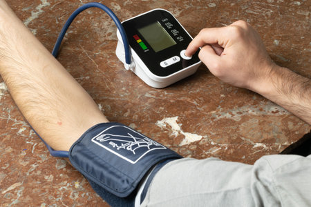 Person taking blood pressure with electronic deviceの写真素材