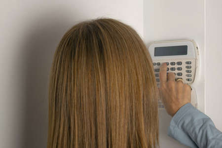 Woman operating on an alarm keypad in a houseの写真素材
