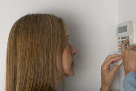 Woman operating on alarm keypad in a houseの写真素材