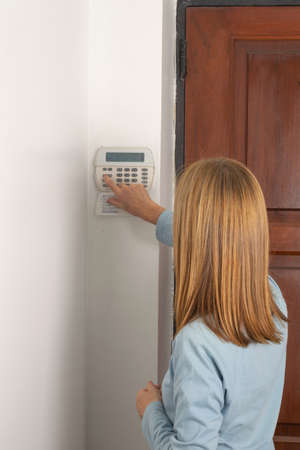Woman operating on an alarm keypad in a houseの写真素材