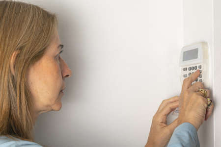 Woman operating keypad alarmの写真素材