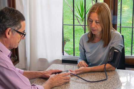 Man taking a woman 's blood pressure with an electronic deviceの写真素材