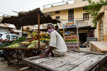 Jaisalmer, Rajasthan / India - July 22 2020 : man notices photographer taking his picture sitting on the hand cart in the middle of the marketのeditorial素材