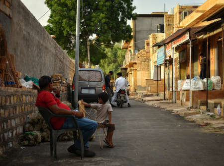 man and child sits on a chair on the street outside of their house.のeditorial素材