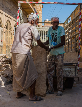 Rajasthan / India - 10 october 2020 : two old daily wage construction worker manually shifts an block of stone from a loading taxiのeditorial素材