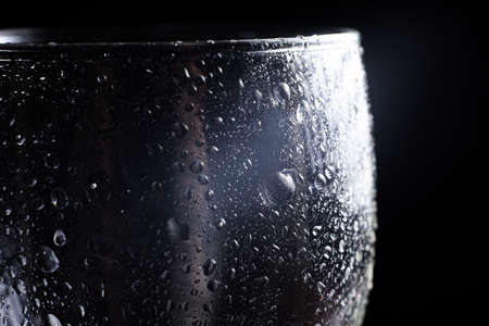 Close up water droplets on black background. Water drops on a glass. Light on a side glass.