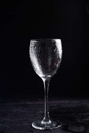 Wine glass in black and white on a black surrface with reflection and water dropsの写真素材