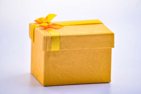A gold giftbox on the white table, birthday, Christmas, Valentine day concept.の写真素材