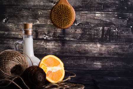 The lay composition with body care products and space for text on dark wood background. a jar of natural cream, a bottle of coconut oil and a ripe orangeの写真素材