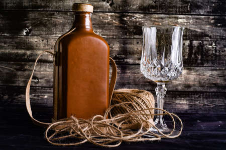 Bottle of whiskey and empty wineglass on a black woodenの写真素材