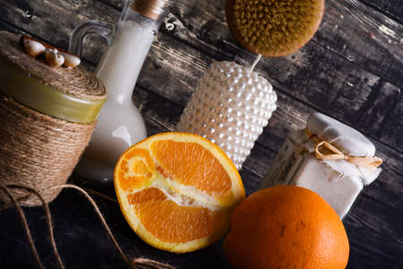 The lay composition with body care products and space for text on dark wood background. a jar of natural cream, a bottle of coconut oil and a ripe orange and candleの写真素材