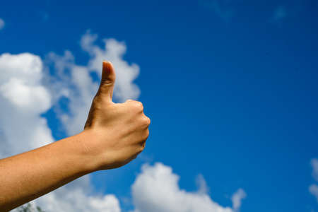 Thumb up in the sky. Hand show thumbs up on a blue skyの写真素材