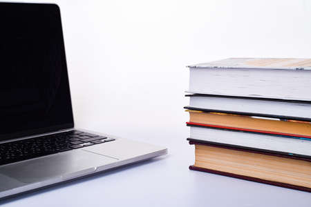 Laptop and stack of books on a white background. With space for letters or text. Quarantine and self-isolation conceptの写真素材