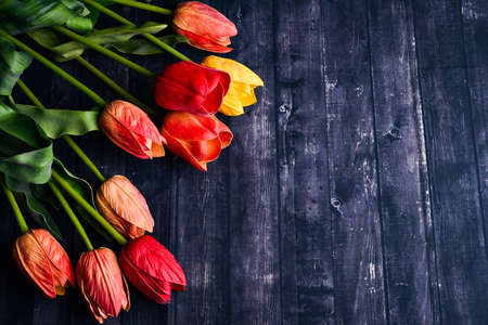 Copy space bouquet of orange and yellow tulips over a rustic wood table top. Flat lay overhead view style.の写真素材