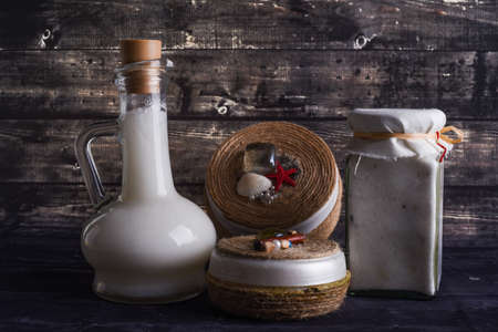 the lay composition with body care products on dark wood background. A jar of natural cream and bottle of coconutの写真素材