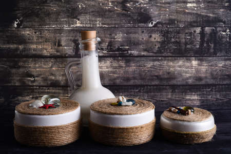 the lay composition with body care products on dark wood background. A jar of natural cream and bottle of coconutの写真素材