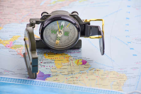 Compass and medical mask on the background of the world map. safe travel conceptの写真素材