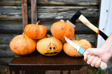 horror scene. A group of dead pumpkins, one pumpkin with an ax in its head. a maniac with a knife kills pumpkins. Halloween conceptの写真素材