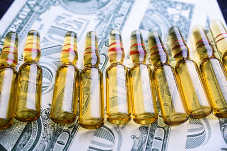 many medical ampoules in a row against the background of green dollars. Close-upの写真素材