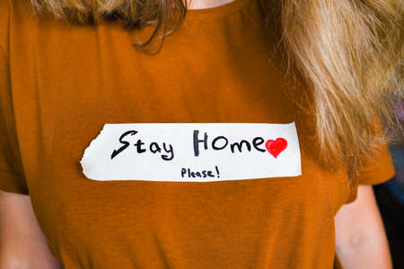young girl in a brown T-shirt with an inscription stay at home. The girl urges to stay at home during the pandemic. self-isolation conceptの写真素材