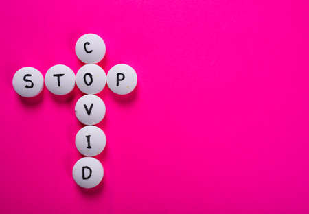 inscription STOP COVID made of white medical pills on a bright pink background. Medicine concept