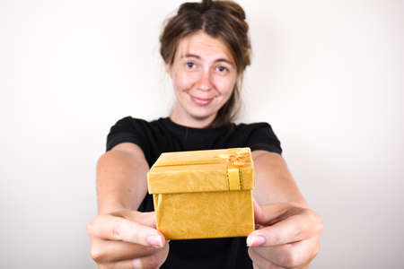 young woman in a black t-shirt on a white background is happy to accepting gift. accept gifts conceptの写真素材