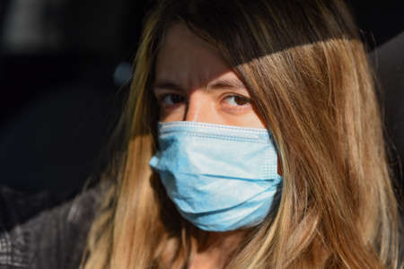 woman wears a medical mask because air pollution or virus is an epidemic in the city. Breathing protection concept. Woman in medical mask looking at the cameraの写真素材