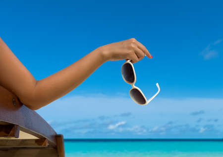 Young girl lying on a beach lounger with glasses in hand on the tropical islandの写真素材