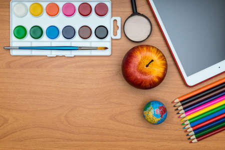 Back to School concept . School supplies and tablet on wooden school desk from above