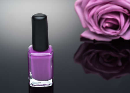 violet nail polish and rose on a black backgroundの写真素材