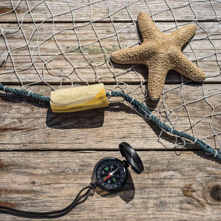 Nautical border with fishing net, sea shells and starfish on a background wooden boardsの写真素材
