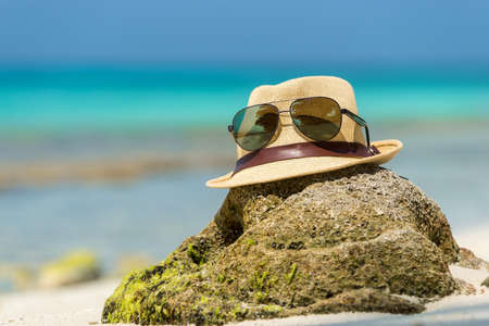 Straw hat, towel beach sun glasses and flip flops on a tropical beachの写真素材