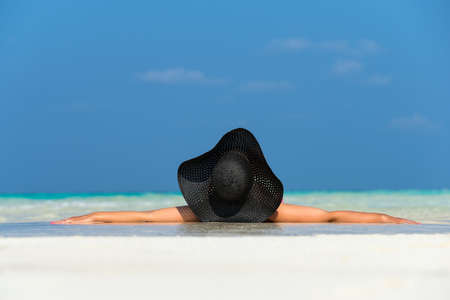 beautiful woman in a hat lying on a tropical beachの写真素材