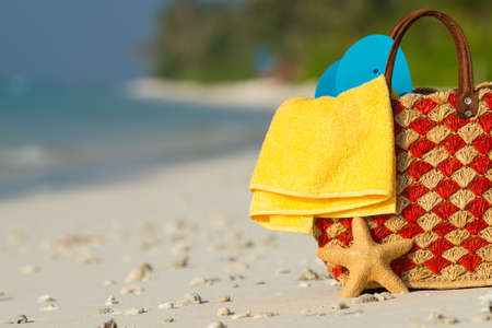 Summer beach bag with shell, towel on sandy beachの写真素材