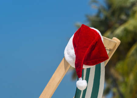 Sun lounger with Santa hat at beautiful tropical beach with white sand and turquoise water, perfect Christmas vacationの写真素材
