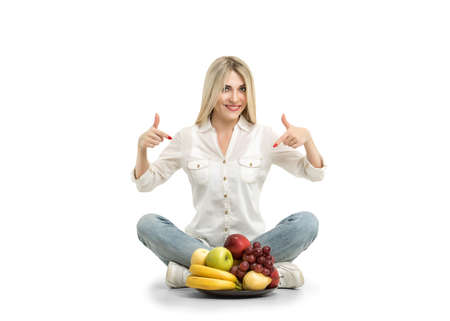 Happy young woman and healthy vegetarian food, fruit. Concept of diet. Low-calorie fruit diet. Diet for weight loss. Vegetarian diet for weight loss. Wellness.の写真素材