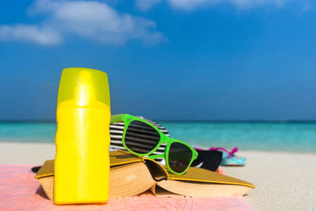 Sunscreen, hat and sunglasses on tropical beachの写真素材