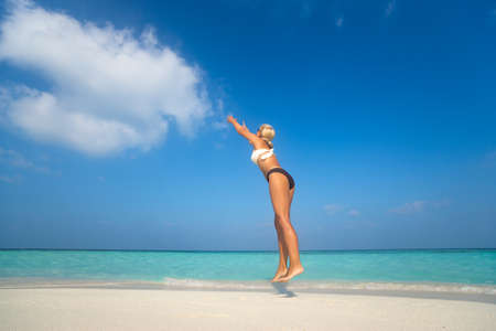 Young woman jumping on the beach, catch cloudの写真素材