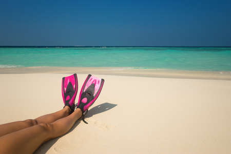 Woman relaxing on summer beach vacation holidays lying in sand. Flippers in legs. Diver fins